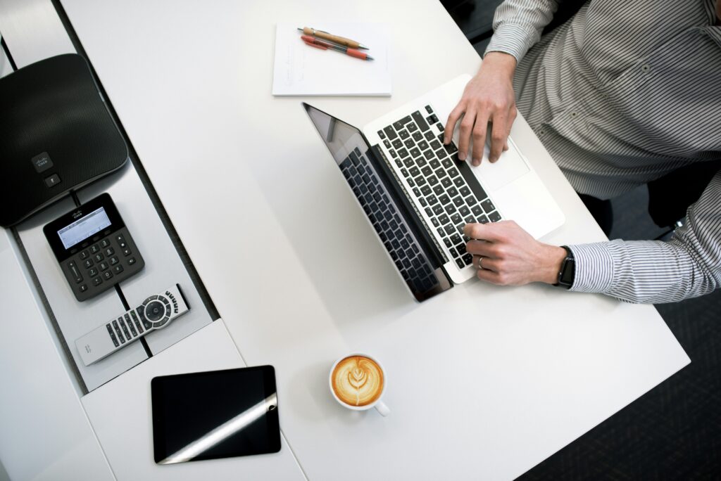 CloudAssist Academy - Upskill across the Microsoft suite and get certified with CloudAssist. Image of a man sitting at his desk working on his laptop. Top-down view.